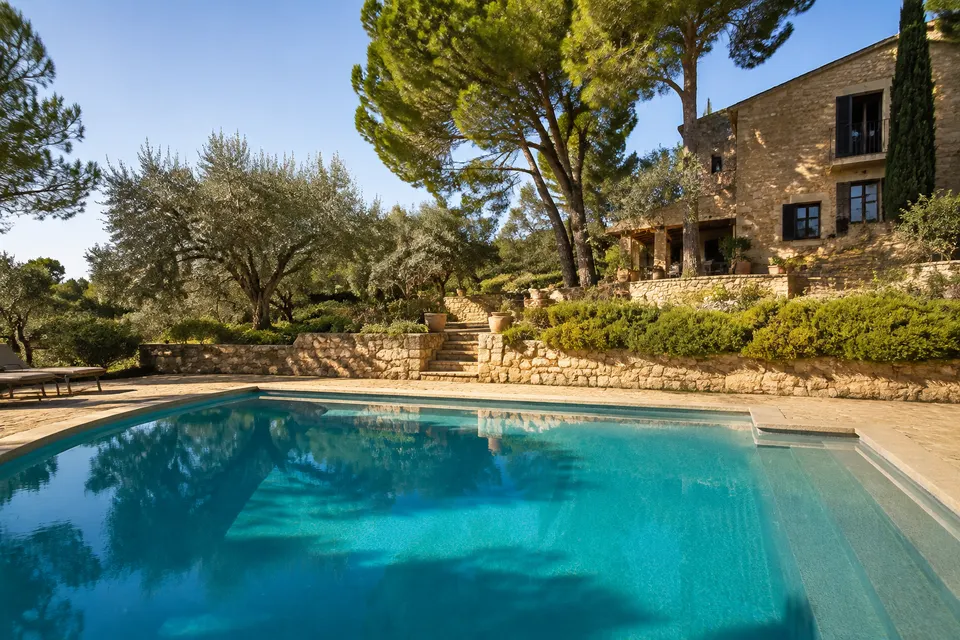Piscina junto a una terraza de piedra y vegetación mediterránea